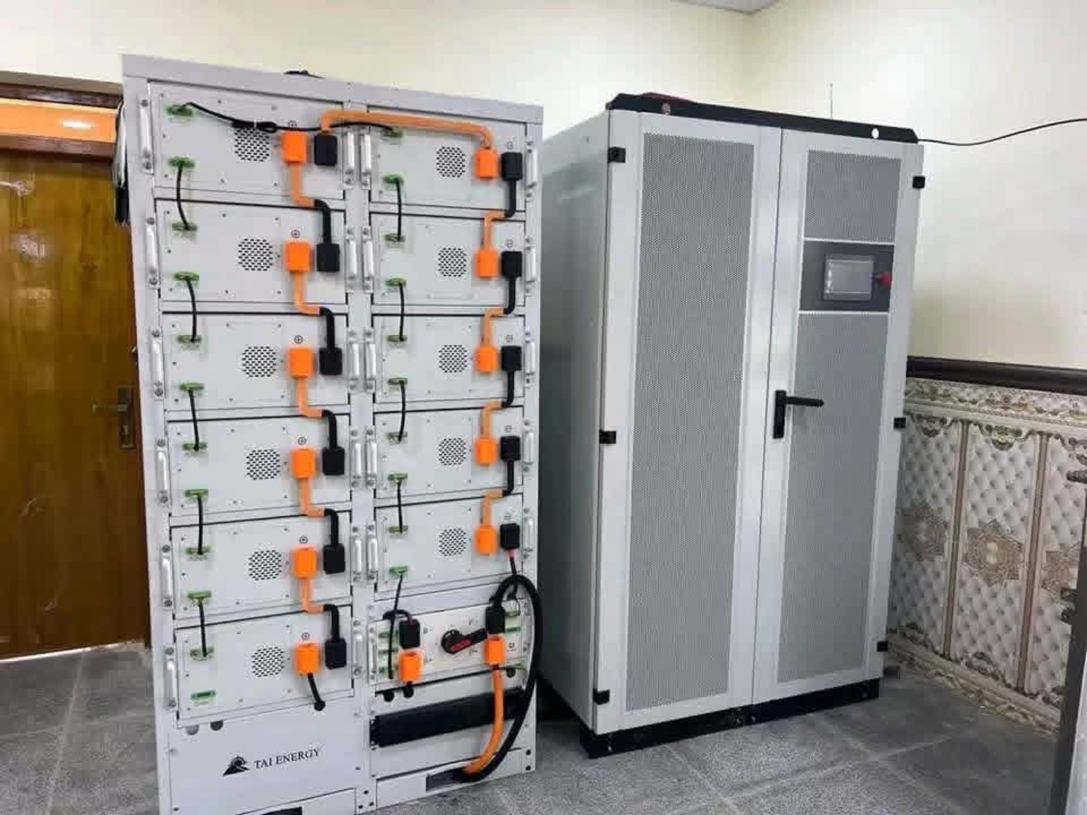 Battery rack beside a tall power cabinet indoors