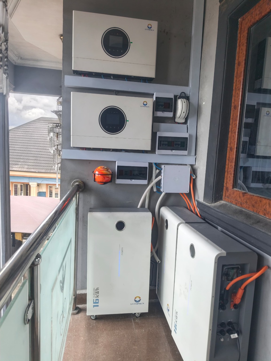 Two wall-mounted inverters above battery units on a residential balcony