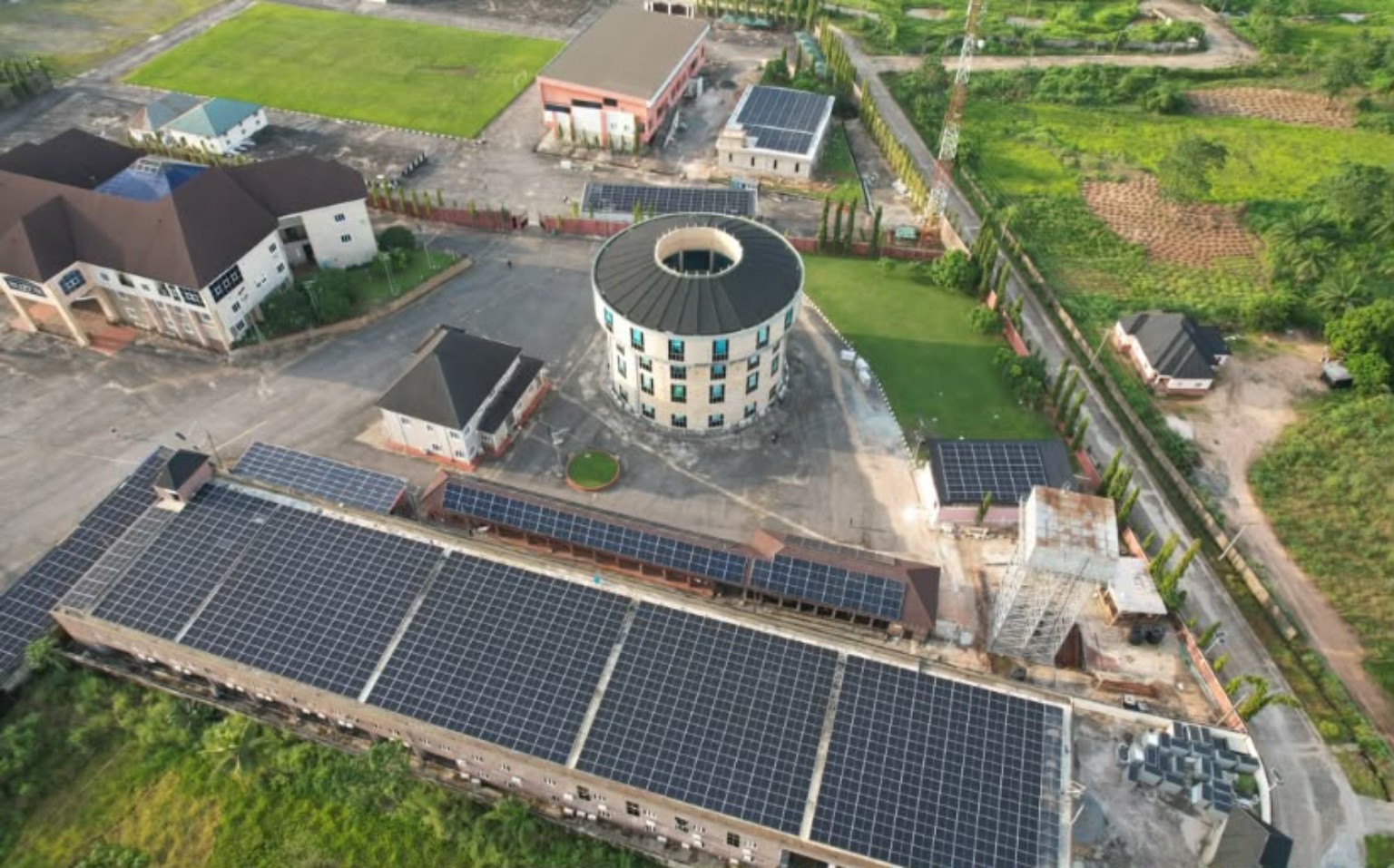 Aerial view of a facility with solar panels covering a large roof and several smaller buildings